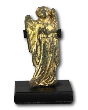 A gilt bronze figure of candle bearing angel. Probably French, 14th century.