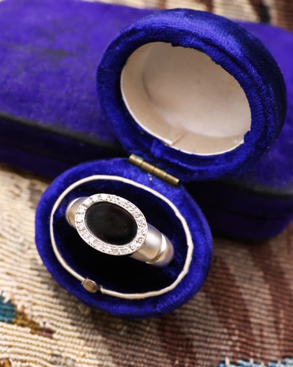 Downstairs at Grays: An 18ct (marked) Brushed White Gold Plaque Ring, with Oval Black Onyx, surrounded by a gallery of Single Cut Diamonds. Circa 1970 - image 1