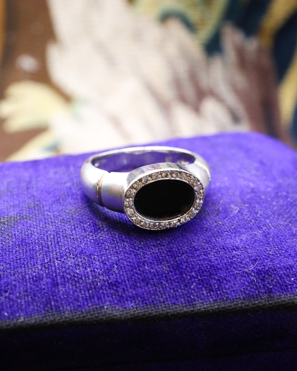 Downstairs at Grays: An 18ct (marked) Brushed White Gold Plaque Ring, with Oval Black Onyx, surrounded by a gallery of Single Cut Diamonds. Circa 1970 - image 2